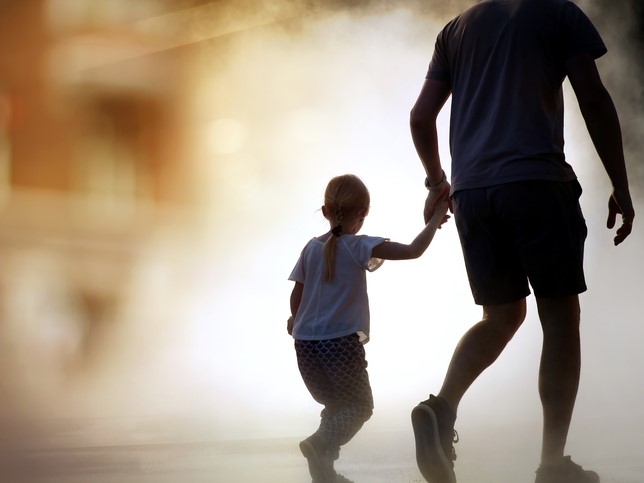 A man walking holding a little girl's hand.